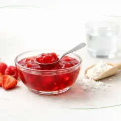 Czy kisiel jest zdrowy? Miseczka z owocowym kisielem, maliny, truskawki, łyżeczka, szklanka wody i skrobia.