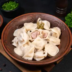 Pielmieni co to? Aromatyczne pierożki z mięsem, podane z kwaśną śmietaną i zieloną pietruszką. Pyszne danie!