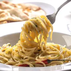 Pyszne spaghetti na widelcu, idealne na trzy pomysły na szybki obiad z makaronem. W tle pieczywo.