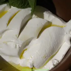 Kremowy ser labneh co to? Delikatny, biały ser z oliwą i miętą, podany w ceramicznej miseczce.