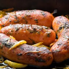 Soczysta kiełbasa z piekarnika jak z grilla, pieczona z cebulką i ziołami. Idealna na obiad!
