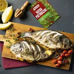 Dwie dorady z grilla, świeże cytryny, limonka i przyprawy tworzą apetyczną kompozycję.
