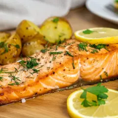 Soczysty łosoś z airfryer, podany z pieczonymi ziemniaczkami i cytryną, posypany świeżym koperkiem.