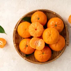 Koszyk pełen soczystych mandarynek, niektóre obrane, kuszą swoim pomarańczowym kolorem.