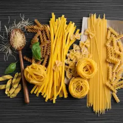 Różne rodzaje makaronu: spaghetti, fusilli, kokardki, tagliatelle, penne, nitki, na drewnianej łyżce.