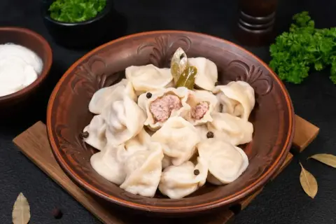 Pielmieni co to? Aromatyczne pierożki z mięsem, podane z kwaśną śmietaną i zieloną pietruszką. Pyszne danie!