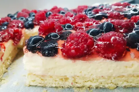 Pyszny biszkopt z galaretką bez kremu, obficie udekorowany malinami i borówkami. Idealny na letnie popołudnie.