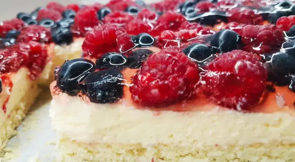 Pyszny biszkopt z galaretką bez kremu, obficie udekorowany malinami i borówkami. Idealny na letnie popołudnie.