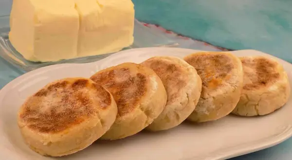 Pięć angielskich muffinek na talerzu, obok kostka masła. Idealne na śniadanie, jak u naszych moskali.