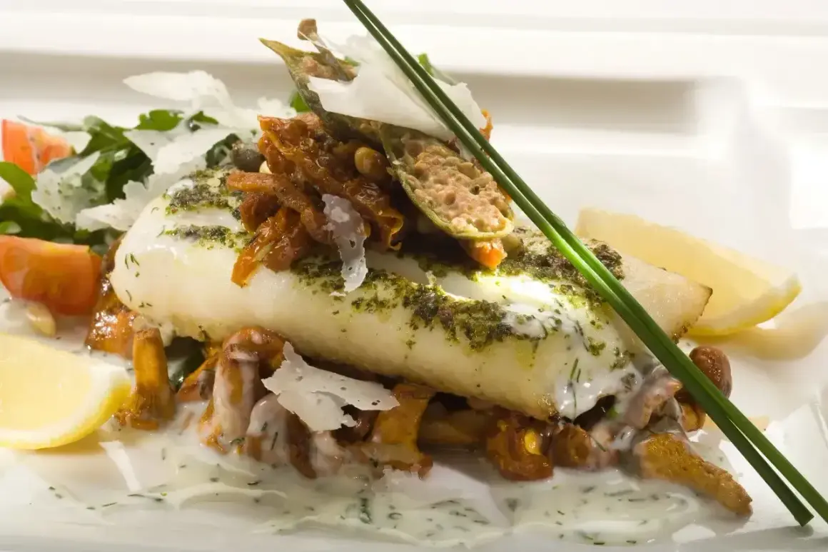Wykwintne danie z rybą halibut, podane z kurkami, pomidorkami i cytryną.