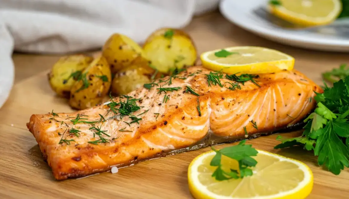 Soczysty łosoś z airfryer, podany z pieczonymi ziemniaczkami i cytryną, posypany świeżym koperkiem.