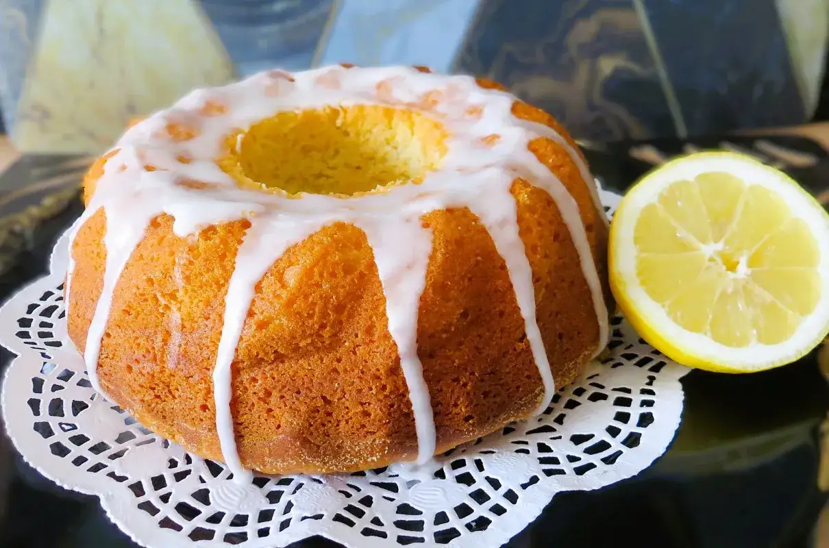 Puszysta babka cytrynowa na oleju Ewy Wachowicz, polana lukrem, obok połówka cytryny.