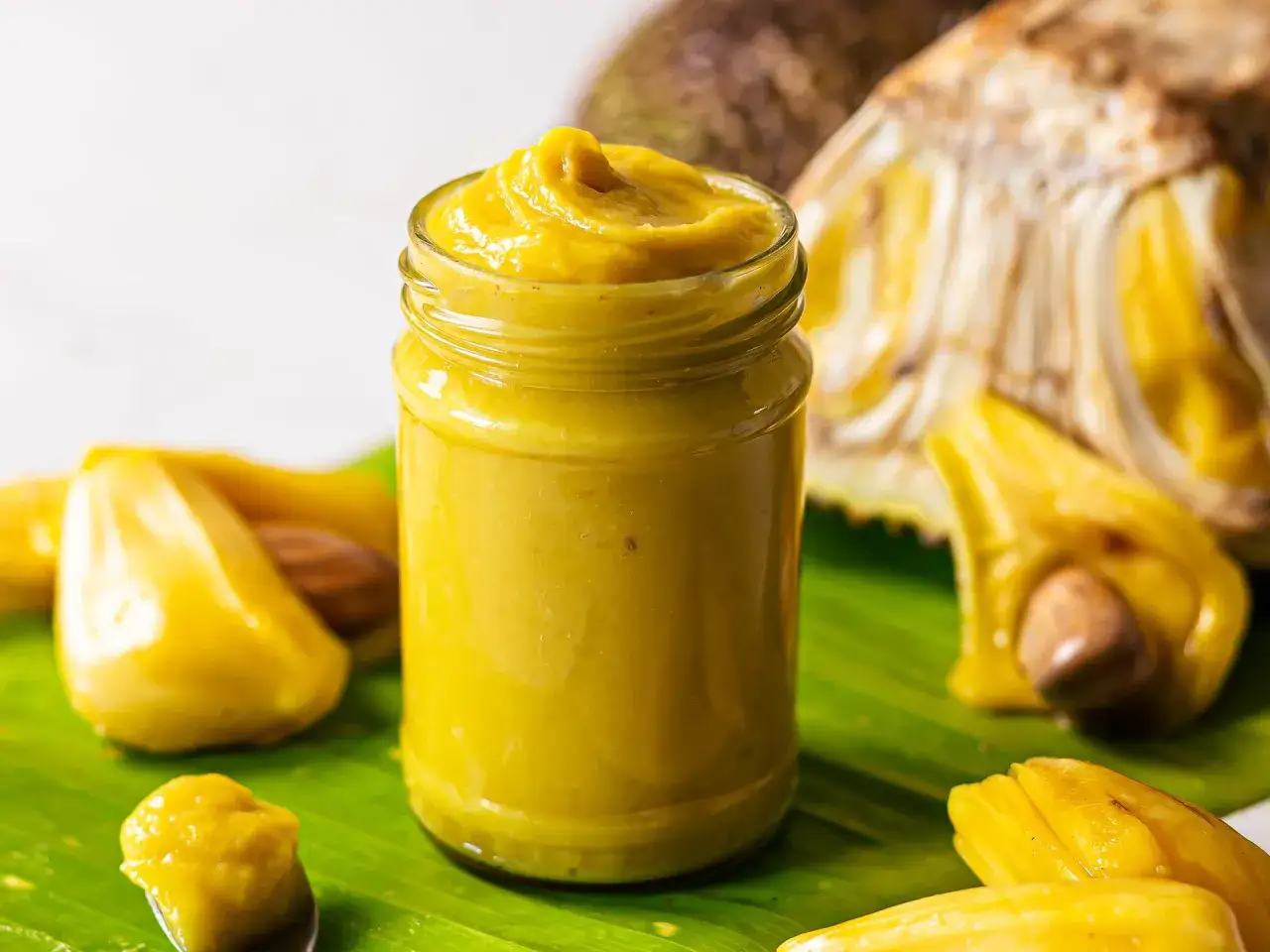 Słoiczek z gęstą, żółtą pastą z jackfruita, obok kawałków owocu. Zastanawiasz się jackfruit co to? To egzotyczny przysmak!
