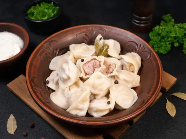 Pielmieni co to? Aromatyczne pierożki z mięsem, podane z kwaśną śmietaną i zieloną pietruszką. Pyszne danie!