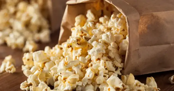 Góra popcornu wysypuje się z papierowej torby. Czy popcorn jest zdrowy? To zależy od sposobu przygotowania.