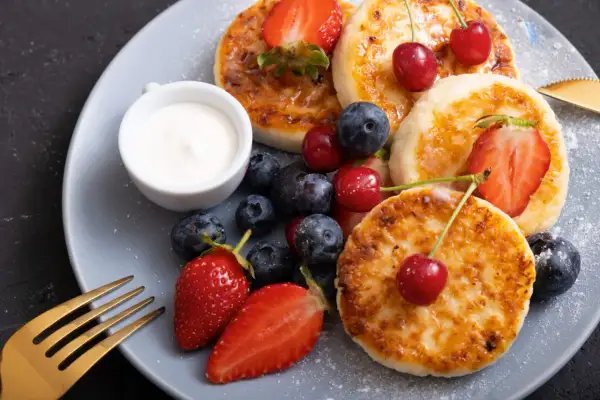 Pyszne placuszki z twarogu, idealne na śniadanie z airfryer, podane z owocami i śmietaną.
