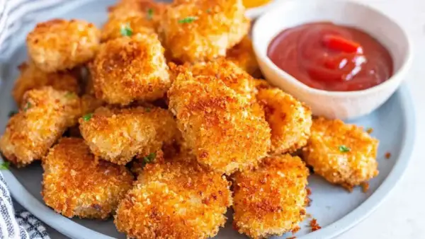 Chrupiące nuggetsy z airfryer na talerzu, obok miseczka z ketchupem. Idealna przekąska dla każdego.