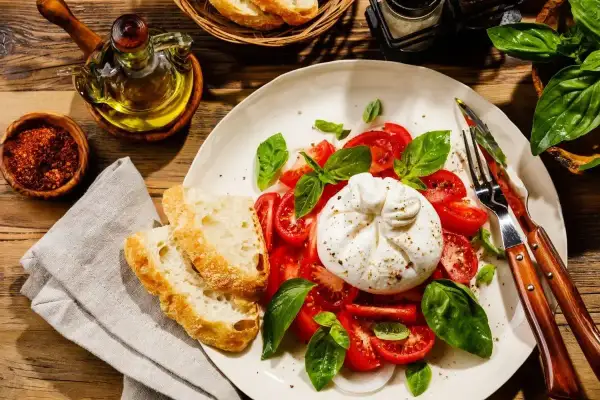 Pyszna burrata co to? Świeża, kremowa burrata z pomidorami, bazylią i chrupiącym pieczywem. Idealna na lekki posiłek.