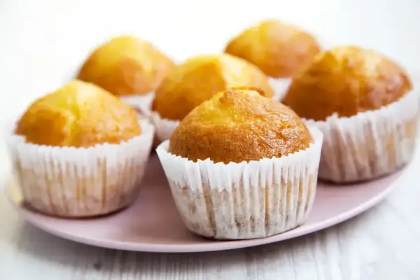 Sześć złotych muffinek na różowym talerzu. Idealne na uniwersalny przepis na muffinki, które zachwycą każdego.