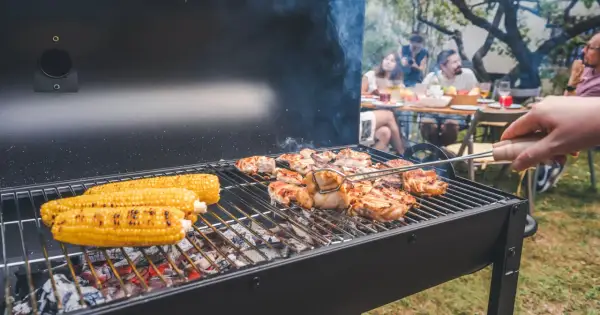 Letnia biesiada z grillowaniem: soczyste kurczaki i kukurydza na ruszcie, w tle rodzina ciesząca się wspólnym posiłkiem.